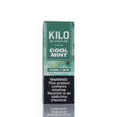 A tall rectangular box of Kilo Cool Mint e-liquid on a white background with a faint reflection below. The packaging is primarily dark green and teal with a black warning label on the lower half containing white text.