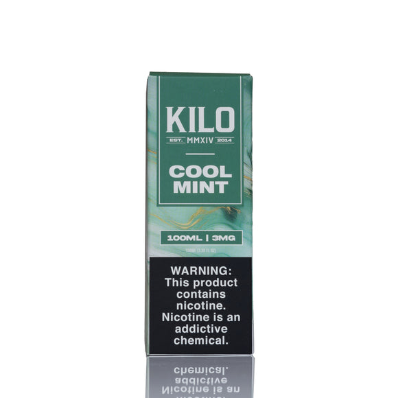 A tall rectangular box of Kilo Cool Mint e-liquid on a white background with a faint reflection below. The packaging is primarily dark green and teal with a black warning label on the lower half containing white text.