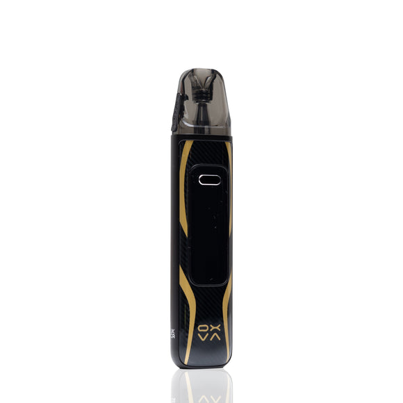 A black and gold Oxva vape device with a carbon fiber pattern, standing vertically on a reflective white surface.