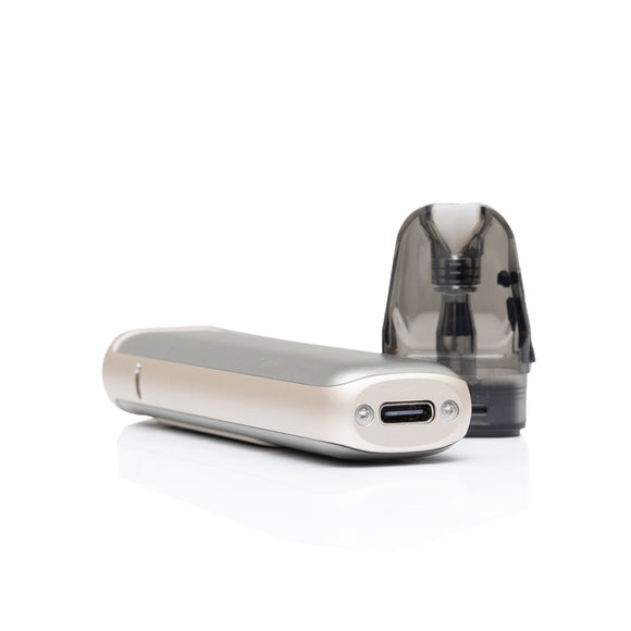 A slim rectangular vape device in a champagne gold finish with a USB-C port, shown alongside a translucent dark gray replacement mouthpiece on a clean white background.